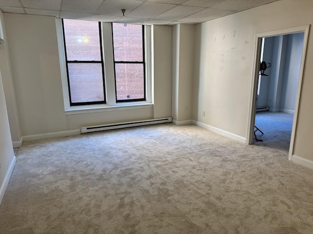 carpeted spare room with a baseboard radiator and a drop ceiling