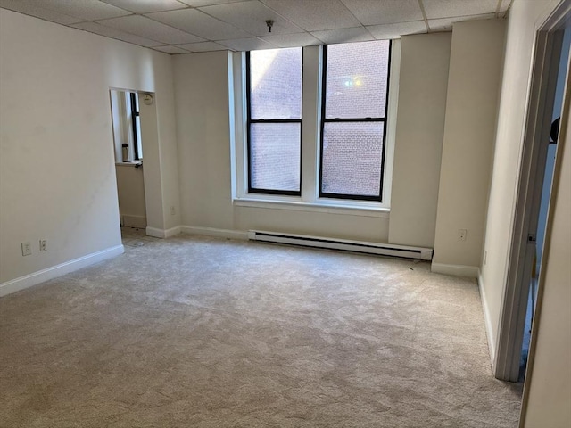 carpeted spare room with a drop ceiling and baseboard heating