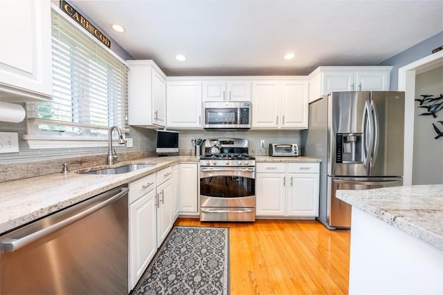19 Longwood Rd Unit 243, Mashpee, MA 02649 - kitchen featuring appliances with stainless steel finishes, a sink, white cabinets, decorative backsplash, and light stone countertops