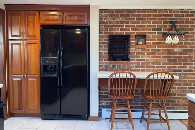 kitchen featuring black refrigerator with ice dispenser, brick wall, light tile patterned flooring, and a baseboard radiator