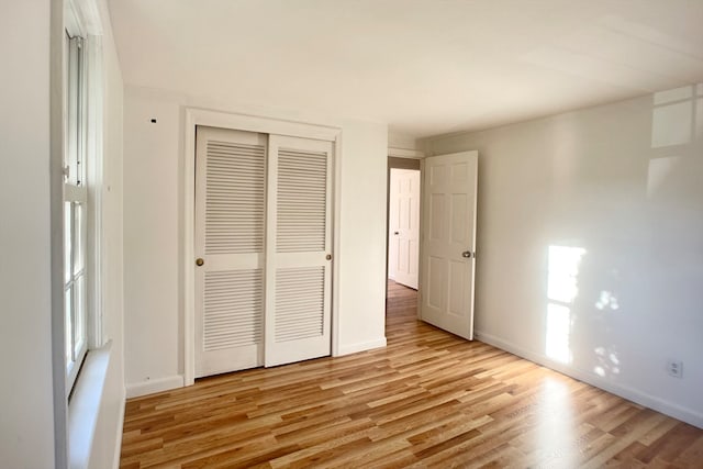 unfurnished bedroom with light wood-type flooring and a closet