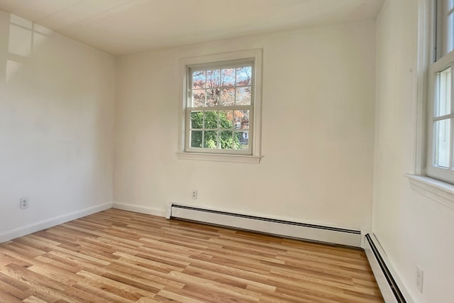 unfurnished room with a baseboard heating unit and light hardwood / wood-style flooring