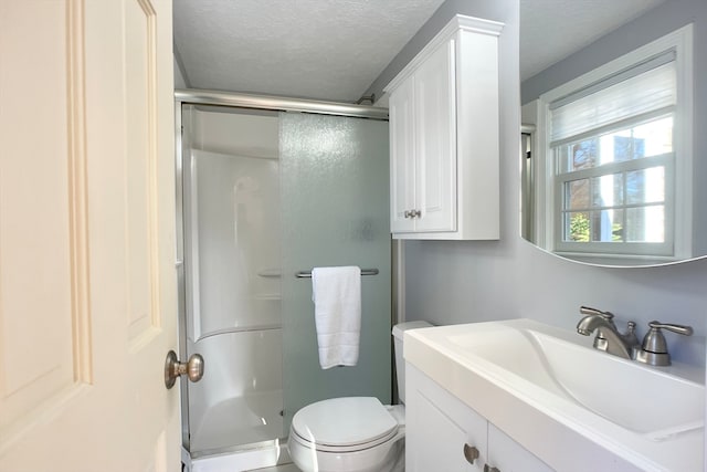 bathroom featuring vanity, a shower with door, a textured ceiling, and toilet