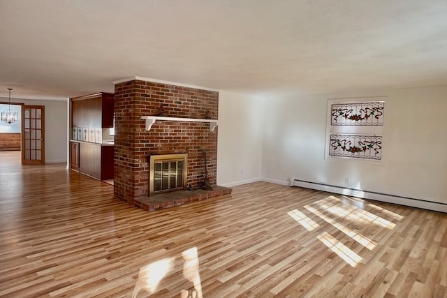 unfurnished living room with a brick fireplace, a baseboard radiator, light hardwood / wood-style flooring, and a chandelier