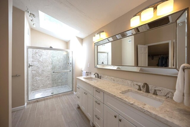 13 Valleywood Rd, Hopkinton, MA 01748 - bathroom with double vanity, a shower stall, vaulted ceiling, baseboards, and a spacious closet