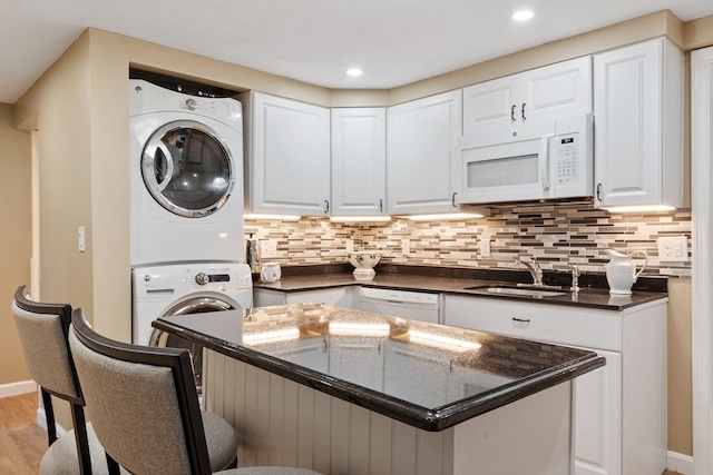 9 New Meadow Rd, Lynnfield, MA 01940 - kitchen with stacked washer and clothes dryer, white appliances, white cabinets, a center island, and tasteful backsplash