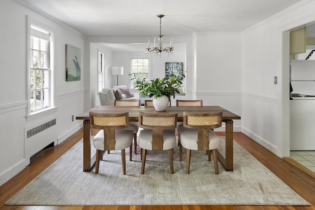 159 Payson Rd, Brookline, MA 02467 - dining room with radiator heating unit, a chandelier, wood finished floors, stacked washing machine and dryer, and crown molding