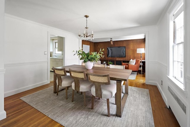 159 Payson Rd, Brookline, MA 02467 - dining room featuring radiator, a chandelier, wood finished floors, crown molding, and baseboards
