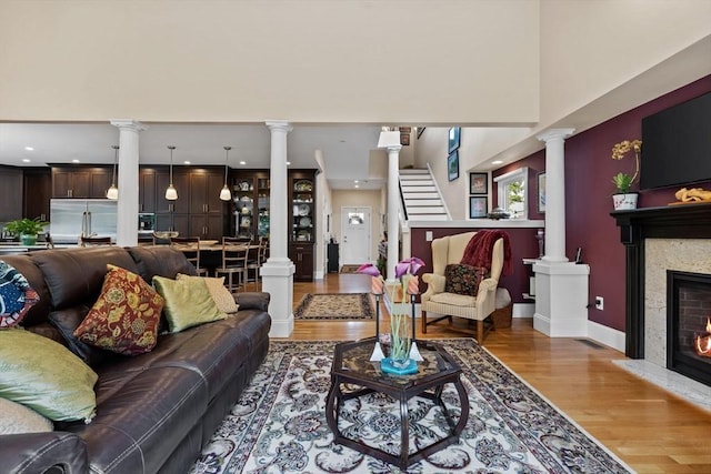 1488 Washington St Unit 1488, Newton, MA 02465 - living area featuring ornate columns, light wood-type flooring, recessed lighting, baseboards, and a warm lit fireplace