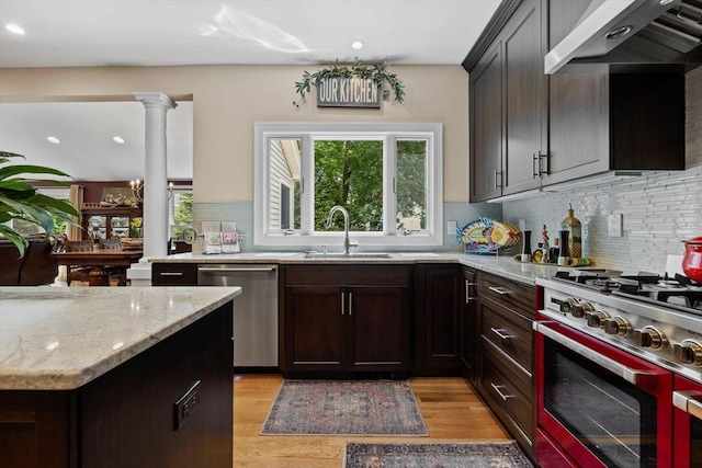 1488 Washington St Unit 1488, Newton, MA 02465 - kitchen featuring appliances with stainless steel finishes, a sink, exhaust hood, tasteful backsplash, and light wood finished floors