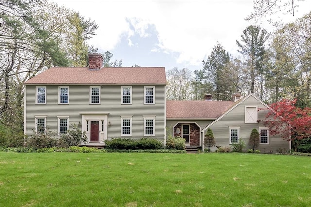 colonial inspired home featuring a chimney and a front lawn