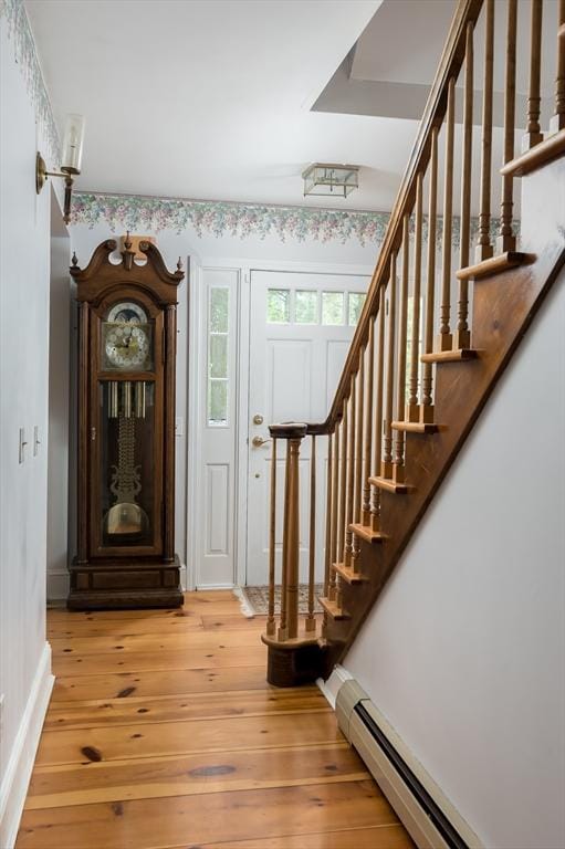 foyer with baseboard heating, stairway, light wood finished floors, and baseboards