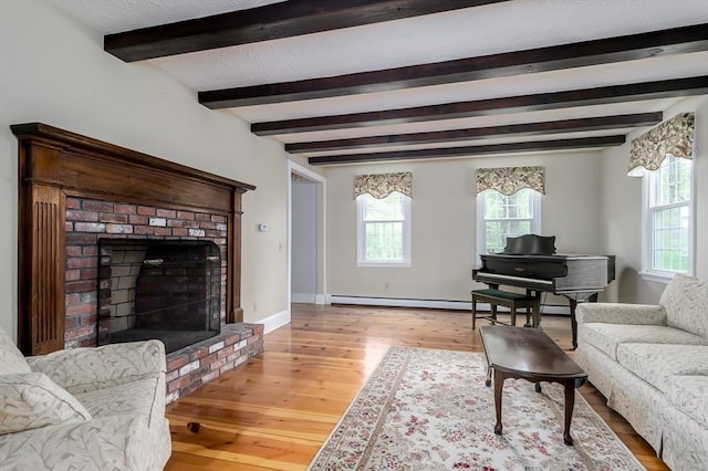 living area with plenty of natural light, baseboard heating, light wood-type flooring, beam ceiling, and baseboards