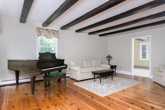living area featuring a baseboard heating unit, wood finished floors, beam ceiling, baseboards, and a textured ceiling