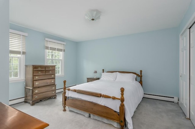 bedroom featuring a baseboard heating unit, light colored carpet, and a closet