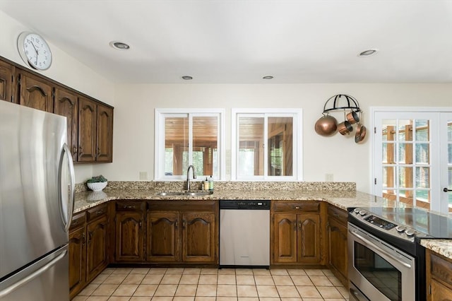 kitchen featuring appliances with stainless steel finishes, a sink, plenty of natural light, light stone counters, and recessed lighting