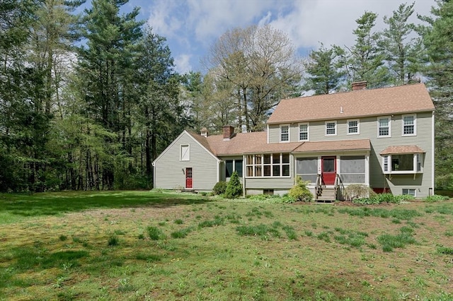back of house with a chimney, a sunroom, and a yard