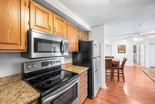39 Parlin St Unit 503, Everett, MA 02149 - kitchen with appliances with stainless steel finishes, light wood-style floors, ceiling fan, brown cabinets, and a textured ceiling