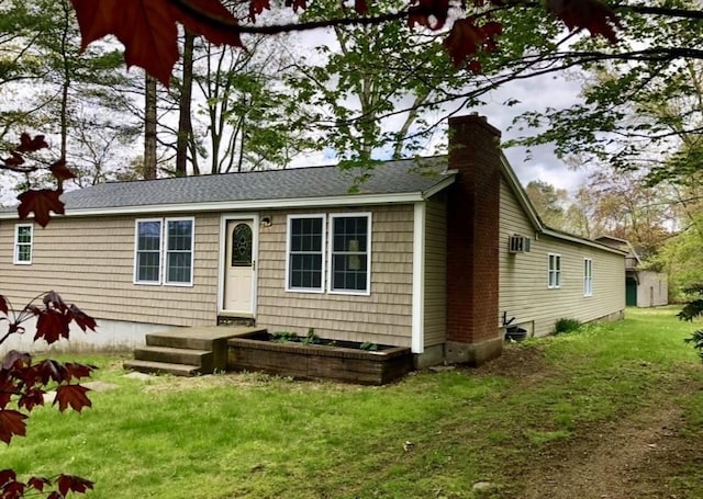 view of front facade featuring a shingled roof, a front yard, and a chimney