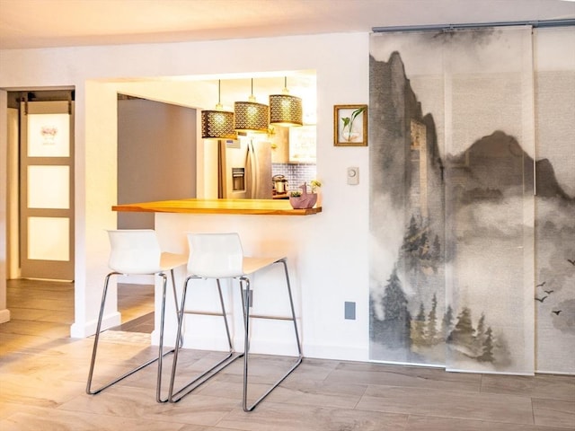 382 Great Rd Unit B 203, Acton, MA 01720 - kitchen featuring stainless steel fridge with ice dispenser, baseboards, a breakfast bar area, light wood finished floors, and tasteful backsplash