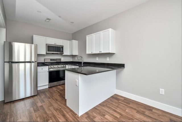 1907 Columbus Ave, Boston, MA 02119 - kitchen featuring appliances with stainless steel finishes, baseboards, a peninsula, white cabinets, and dark countertops