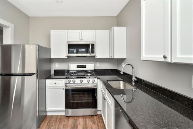1907 Columbus Ave, Boston, MA 02119 - kitchen featuring appliances with stainless steel finishes, a sink, white cabinetry, dark stone counters, and light wood-style floors