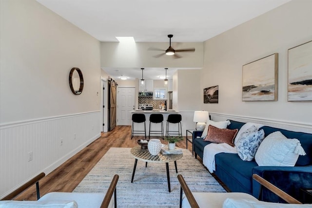 81 Fletcher Ln Unit I, Brewster, MA 02631 - living room with ceiling fan, a wainscoted wall, light wood finished floors, a barn door, and vaulted ceiling