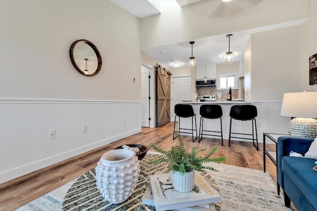 81 Fletcher Ln Unit I, Brewster, MA 02631 - living room featuring light wood finished floors, a barn door, and wainscoting