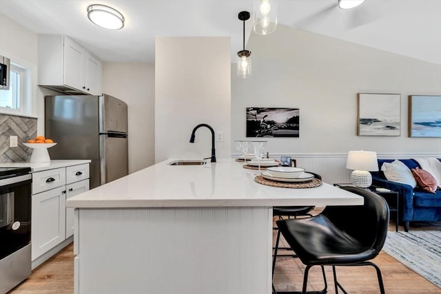 81 Fletcher Ln Unit I, Brewster, MA 02631 - kitchen featuring stainless steel appliances, light wood finished floors, a breakfast bar area, light countertops, and a wainscoted wall
