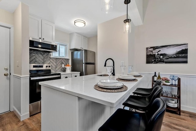 81 Fletcher Ln Unit I, Brewster, MA 02631 - kitchen featuring appliances with stainless steel finishes, white cabinets, light wood-style flooring, light stone counters, and wainscoting