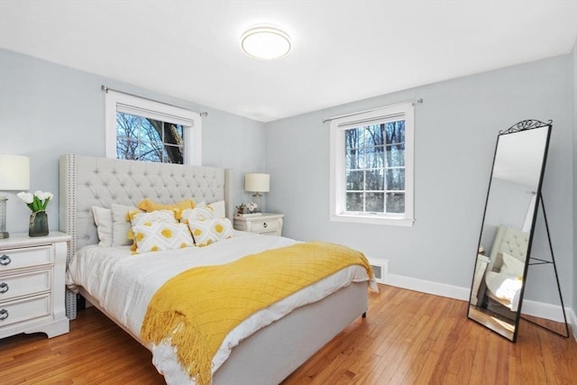 bedroom featuring light wood-type flooring, multiple windows, baseboards, and visible vents