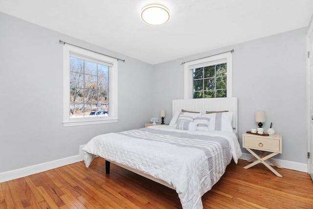 bedroom with light wood-style flooring, multiple windows, and baseboards