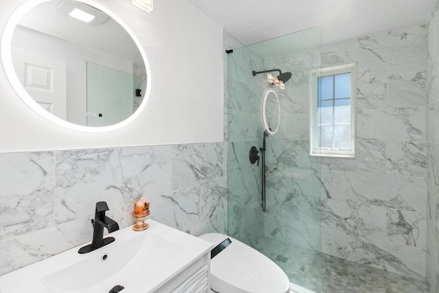 bathroom with vanity, a wainscoted wall, a marble finish shower, tile walls, and toilet