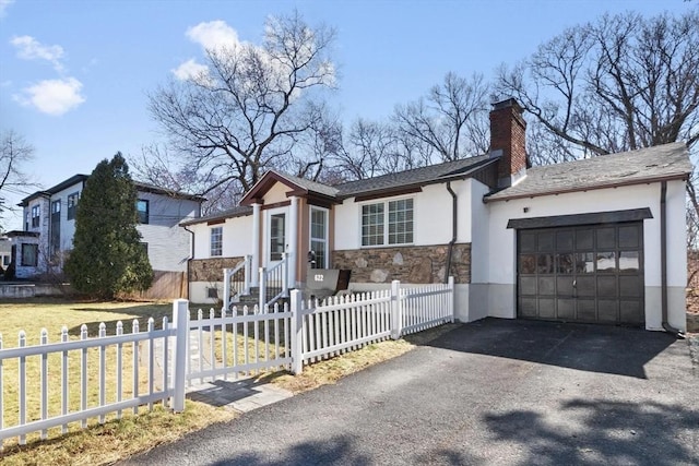 ranch-style home with a fenced front yard, stucco siding, a chimney, a garage, and stone siding