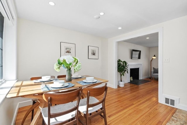 dining area featuring baseboards, visible vents, recessed lighting, a brick fireplace, and light wood-type flooring