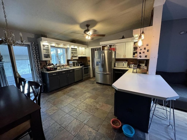 kitchen with white cabinets, a breakfast bar area, decorative light fixtures, kitchen peninsula, and stainless steel appliances