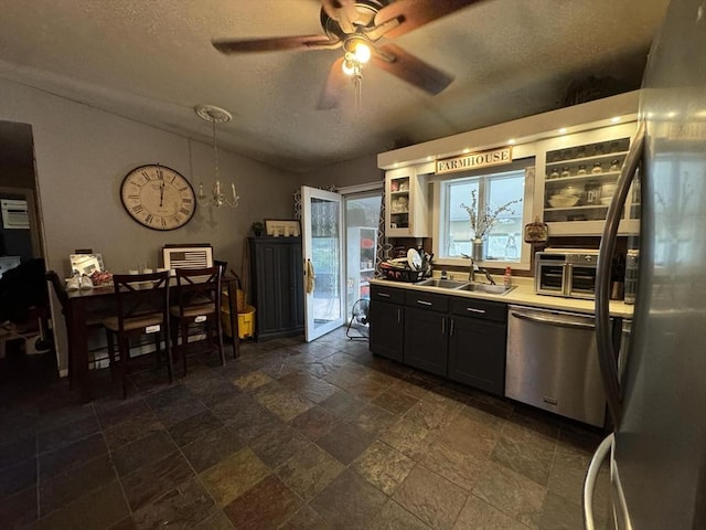 kitchen with a textured ceiling, sink, stainless steel appliances, and ceiling fan with notable chandelier