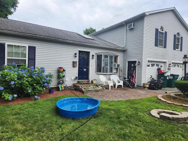 rear view of house featuring a lawn, cooling unit, a garage, and a patio area