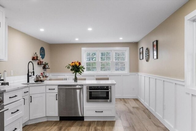 12 Salem St Unit 2, Haverhill, MA 01835 - kitchen featuring a sink, white cabinetry, appliances with stainless steel finishes, a peninsula, and wainscoting