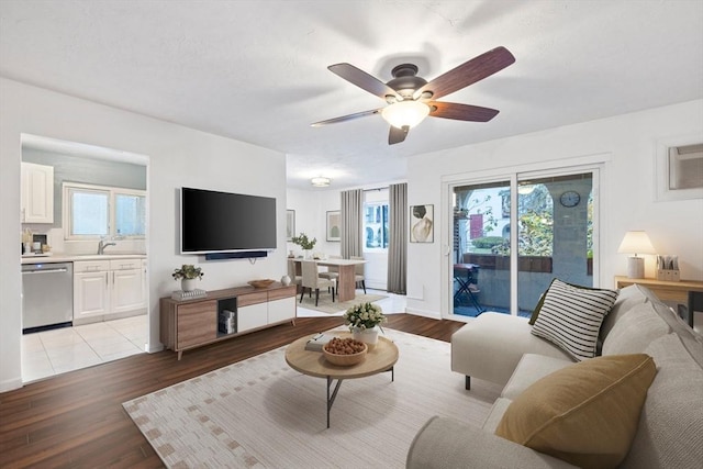 living room featuring light wood-type flooring, ceiling fan, and sink