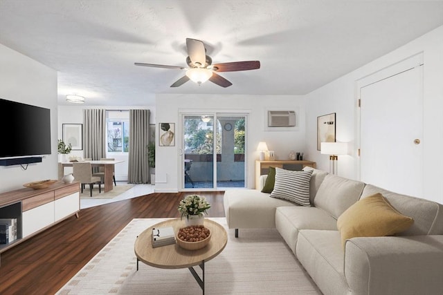 living room featuring ceiling fan, light hardwood / wood-style flooring, and a wall mounted air conditioner