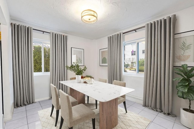 dining space with light tile patterned floors, a textured ceiling, and a wealth of natural light