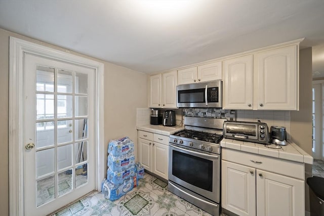 1 Chapin Cir, Randolph, MA 02368 - kitchen featuring appliances with stainless steel finishes, tile countertops, backsplash, white cabinetry, and light tile patterned floors