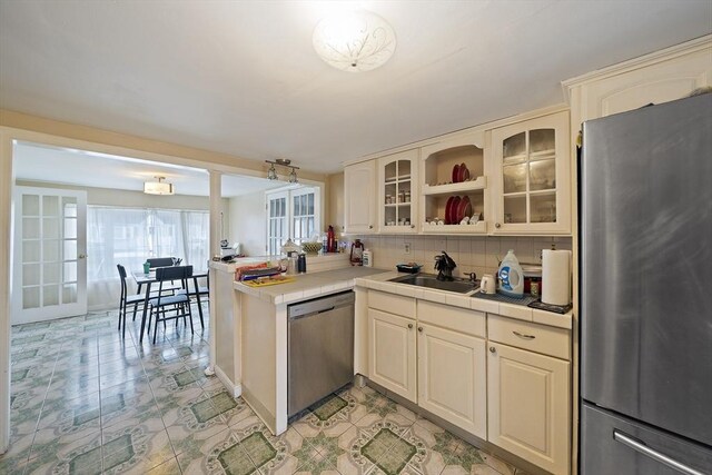 1 Chapin Cir, Randolph, MA 02368 - kitchen featuring appliances with stainless steel finishes, tasteful backsplash, a peninsula, glass insert cabinets, and tile countertops
