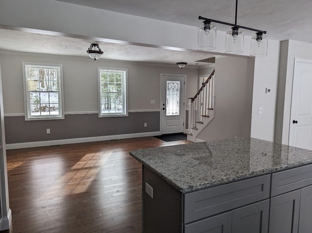 kitchen with dark hardwood / wood-style floors, light stone countertops, decorative light fixtures, gray cabinets, and a textured ceiling