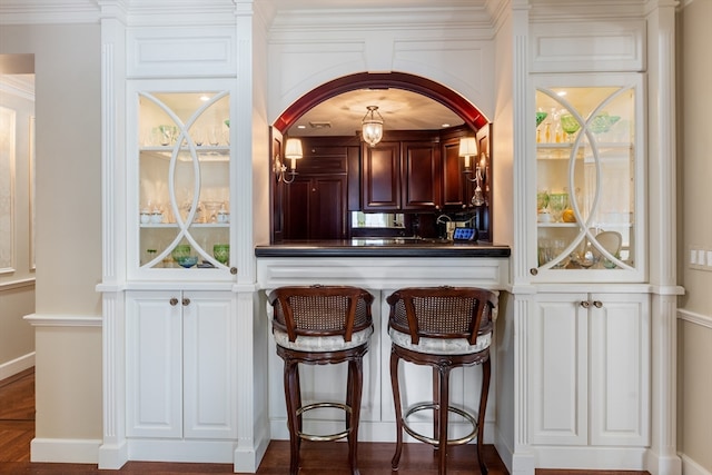 bar featuring white cabinets and ornamental molding