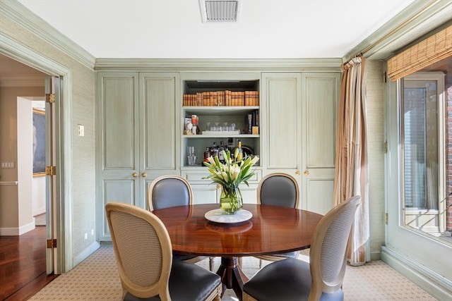 dining space with built in features, light wood-type flooring, and ornamental molding