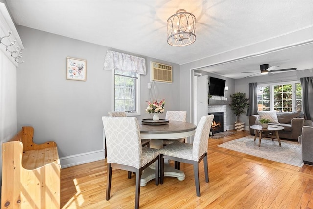 212 Broadway St, Wakefield, MA 01880 - dining space featuring an AC wall unit, light wood finished floors, a brick fireplace, baseboards, and a chandelier