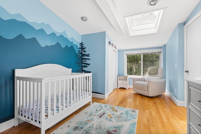 212 Broadway St, Wakefield, MA 01880 - bedroom with a skylight, light wood-style floors, baseboards, and a nursery area