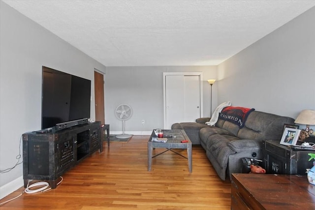 living room with light wood-style flooring, baseboards, and a textured ceiling